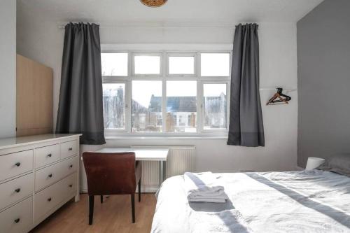 a bedroom with a bed and a desk and a window at Large Modern Apartment with Garden Sleeps 10 Guests in London