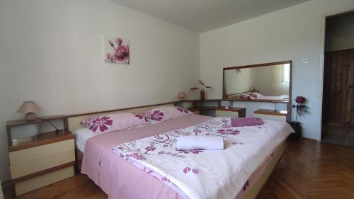 a bedroom with a bed with pink sheets and a mirror at Apartman CELIJA in Barban