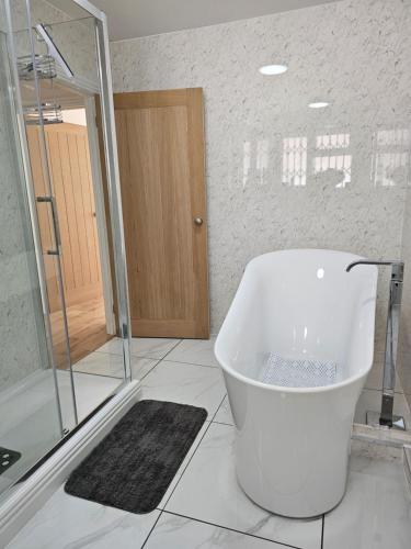 een witte badkamer met een bad en een douche bij Charming 1-Bed Apartment in Cromer Town Centre in Cromer