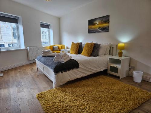 1 dormitorio con 1 cama con almohadas amarillas y alfombra en Charming 1-Bed Apartment in Cromer Town Centre, en Cromer