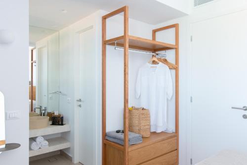 uma casa de banho com um armário de madeira e um roupão branco em Plethora Luxury Suites em Rodhiá