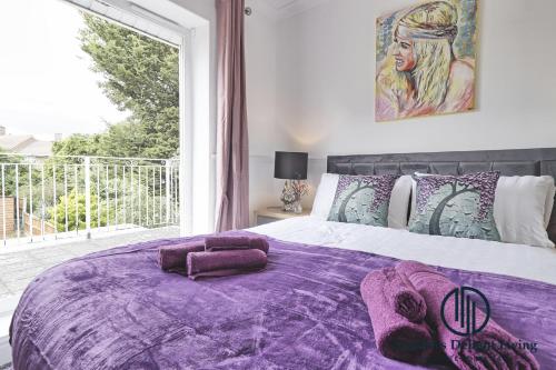 Purple Velvet - 2 Bed Home Spacious - Basildon Essex Upto 5 Guests, Free Wifi , Free Parking في باسيلدون: غرفة نوم مع سرير أرجواني مع نافذة كبيرة