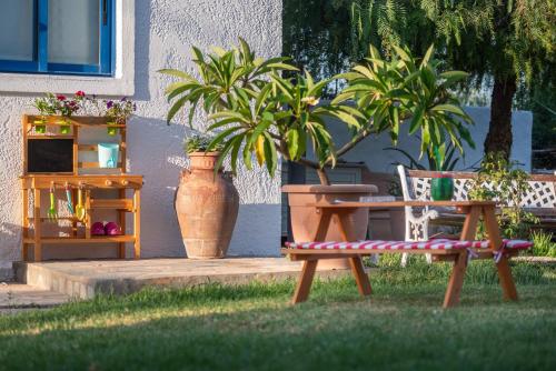 a table and a bench in the grass with plants at To Pyrgaki Kos in Kos Town