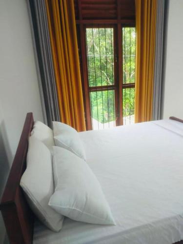 Un dormitorio con una cama con almohadas blancas y una ventana en Oasis Suite, en Kandy