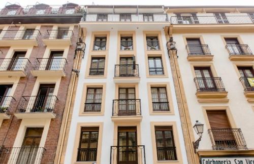 Edificio alto de color blanco con ventanas y balcones en Pensión San Vicente, en San Sebastián