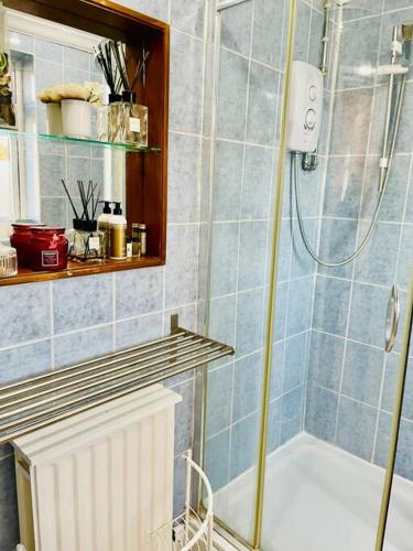 a blue tiled bathroom with a shower and a tub at The Princes Dartford Stunning Entire Space in Kent