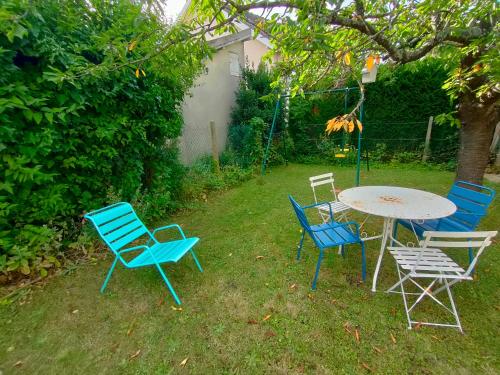 four chairs and a table in a yard at Maison d'hôtes les roses trémières in Saclay
