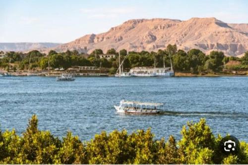 two boats on a large body of water with mountains at West Bank Guest House in Luxor