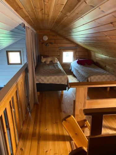 1 dormitorio con 2 camas en una cabaña de madera en Syöte Huuhkamajat Cottage, en Syöte