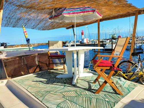 une table, des chaises et un parasol sur un bateau dans l'établissement 1 ou 2 chambres cosy sur une charmante pénichette de 11 m - Pour plus de détails, veuillez consulter notre profil, à Marseillan