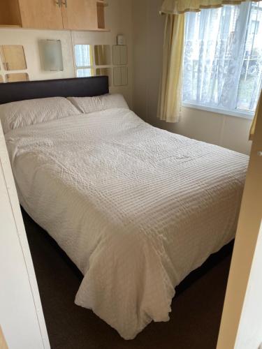uma grande cama branca num quarto com uma janela em Dunlin Dell at Thornwick Bay, Haven site em Flamborough