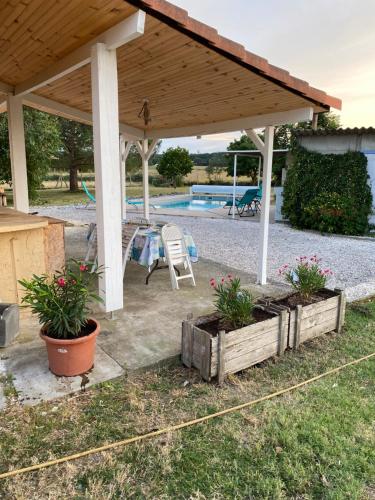 einen Pavillon mit einem Tisch, Stühlen und einem Pool in der Unterkunft Chambre + SDB + Piscine in Grenade-sur-Garonne