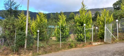 a fence on the side of a road with trees at Aden Valley Resort in Kanthalloor