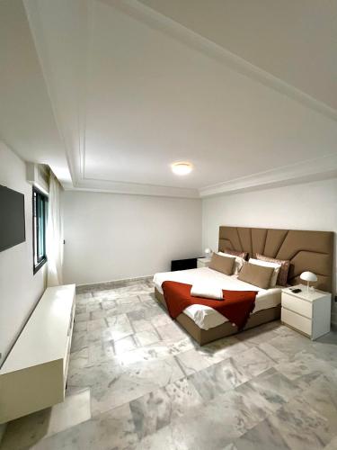 a bedroom with a king sized bed and a couch at Duplex moderne à 1 minute à pied de la plage- Résidence Miramar Mohammedia in Mohammedia
