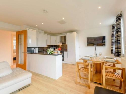 a kitchen and living room with a table and a couch at The beautifully central Flat 3 The Cobourg Tenby Sat to Sat booking only in school summer holidays in Pembrokeshire