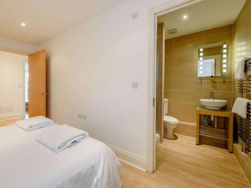a bathroom with a white bed and a sink at The beautifully central Flat 3 The Cobourg Tenby in Pembrokeshire