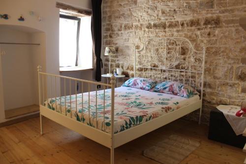 - une chambre avec un lit en métal dans un mur de briques dans l'établissement Casa Torre dell'Angelo, à Bitonto