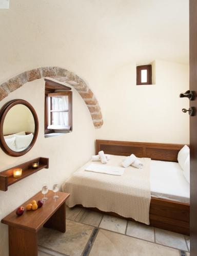 a room with a bed and a mirror and a table at Bastione Malvasia Hotel (ex New Malvasia) in Monemvasia