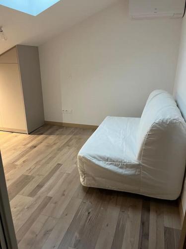 1 dormitorio con cama blanca y suelo de madera en Loft style industriel, en Bagnols-sur-Cèze