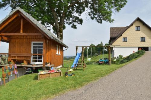 uma pequena casa com um parque infantil e um baloiço em Dürrenbartleshof em Breitnau