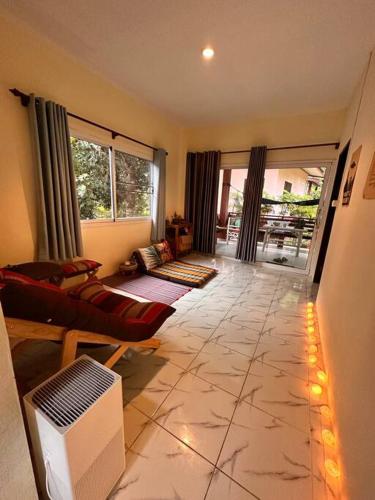 a living room with a couch and a television on a tile floor at Cozy Garden House in Kohphangan! in Ban Nua