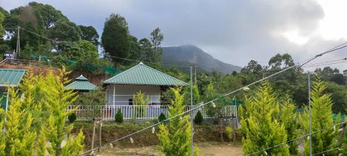 a house with a mountain in the background at Aden Valley Tent Stay , kanthalloor in Kanthalloor