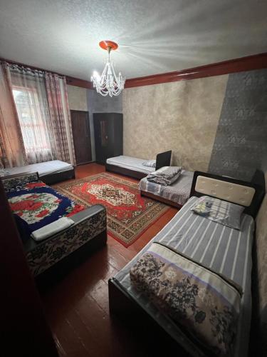 Habitación con 3 camas y lámpara de araña. en Lovely home for you, en Osh