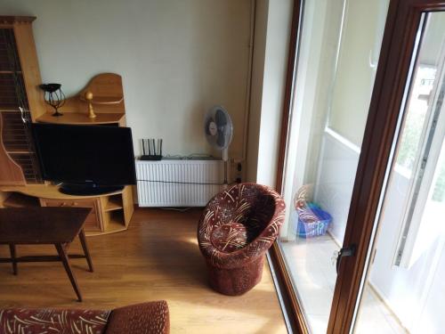 sala de estar con silla y TV en Itaja Apartment 91, en Šiauliai