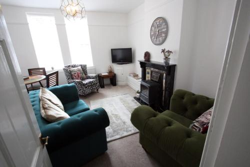 a living room with two green chairs and a fireplace at Lymm Village Apartment in Lymm