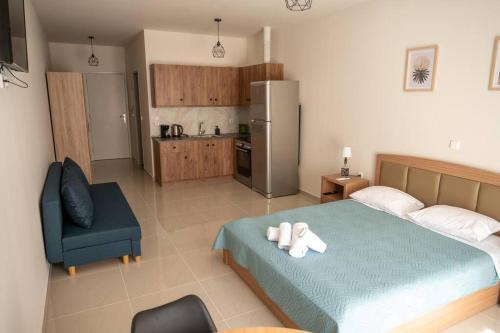 een slaapkamer met een bed en een stoel en een keuken bij Anesis Airport rooms 204 in Koropíon