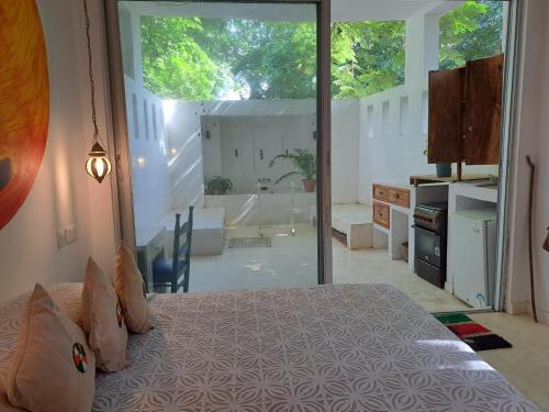 a bedroom with a bed and a large glass door at Manta Cottage - Forest view in Galu