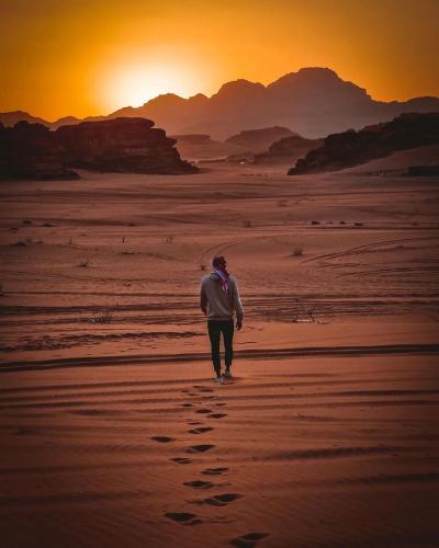 a man walking on the beach at sunset at Sun Luxury Rum Camp in Wadi Rum