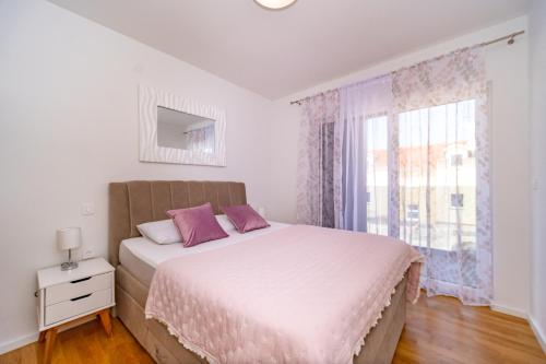 a bedroom with a bed with purple pillows and a window at Spacious one bedroom apartment Lana in Postira