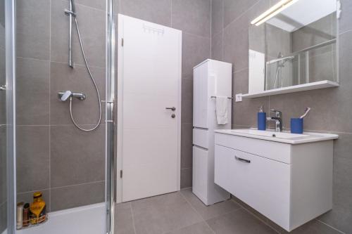 a white bathroom with a shower and a sink at Spacious one bedroom apartment Lana in Postira