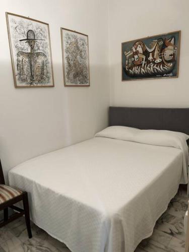 ein weißes Bett in einem Zimmer mit zwei Bildern an der Wand in der Unterkunft Tiberia Apartment in Rom