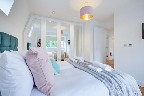- une chambre avec un grand lit blanc et des oreillers dans l'établissement Stylish Apt with Balcony and easy central access, à Londres