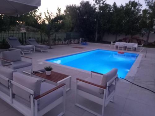 a swimming pool with two chairs and a table next to it at Villa Evàlia - Private Villa With Pool -Malakonda ,Eretria ,Greece in Eretria