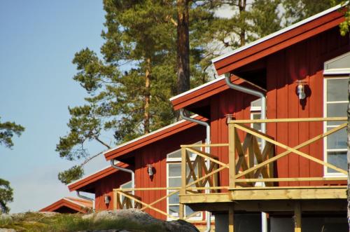 a red house with a balcony in the woods at Skärgårdsbyn S:t Anna in Mon