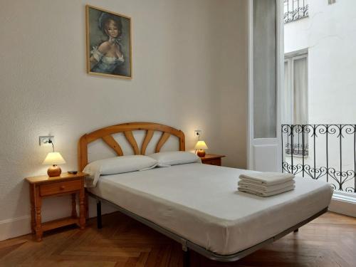 a bedroom with a bed and two lamps and a window at Hostal Miralva in Madrid
