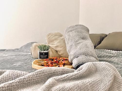 a person in gray socks with a plate of food on a bed at HeyMuji Projector-Netflix-Darts-Near Lotus in Kluang