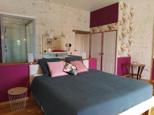 una camera da letto con un grande letto con cuscini rosa di Gite Modes et Café a Épargnes