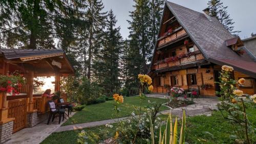 a large wooden house with people sitting in the yard at Holiday Home Tirol in Vlasic