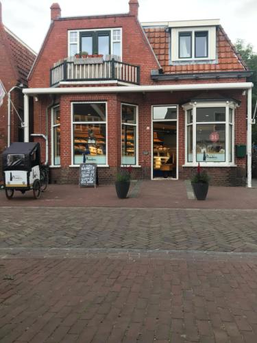 een winkel op een stenen straat met een kar voor bij Logeren bij de bakker in Schiermonnikoog