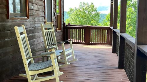 two chairs sitting on the porch of a house at Mistletoe Cabin- Private cabin w views, Hottub, pet friendly in Murphy