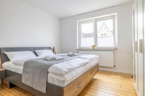 a white bedroom with a large bed with towels on it at Modernes Zuhause - Küche - Top Anbindung - High WLAN in Holzwickede