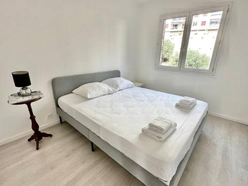 a white bedroom with a bed and a window at Superbe appartement neuf - Plage à 5 min à pied in Nice