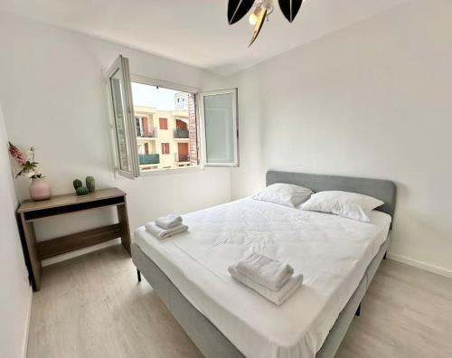 une chambre avec un lit avec des draps blancs et une fenêtre dans l'établissement Superbe appartement neuf - Plage à 5 min à pied, à Nice