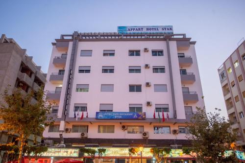 a white building with a sign on top of it at Appart Hotel Star in Tangier