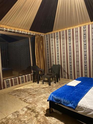 WADi RUM ALi CAMP في وادي رم: غرفة نوم بسرير وبيانو في خيمة