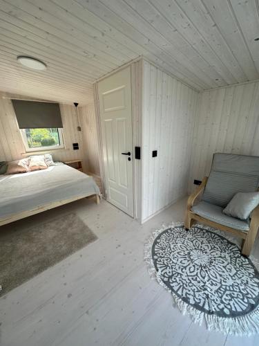 1 dormitorio con 1 cama, 1 silla y 1 alfombra en Fully equipped new tiny-house, en Kuressaare